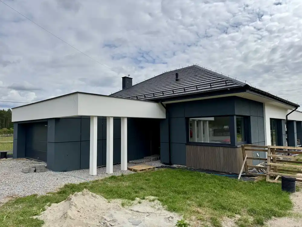 Narożnik domu z podcieniem, bramą garażową i oknem nad okładziną z lameli, Homekoncept 70, Leżajsk